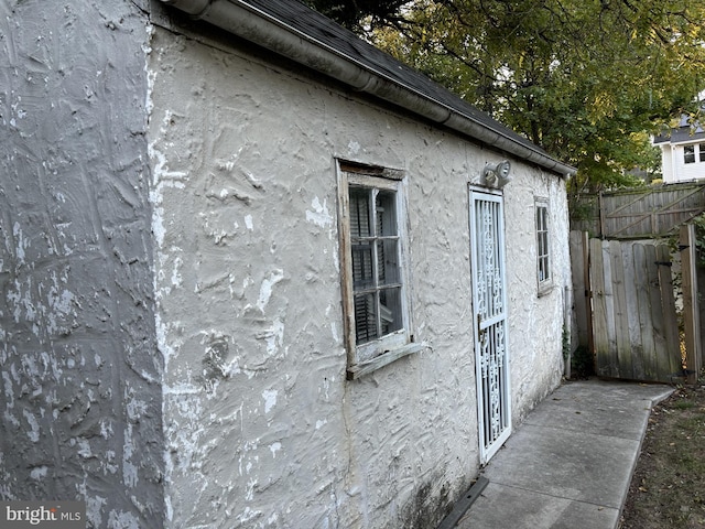 view of side of property with stucco siding and fence