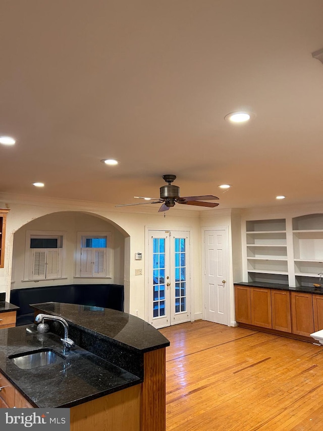 kitchen featuring dark stone counters, french doors, a sink, and light wood-style floors
