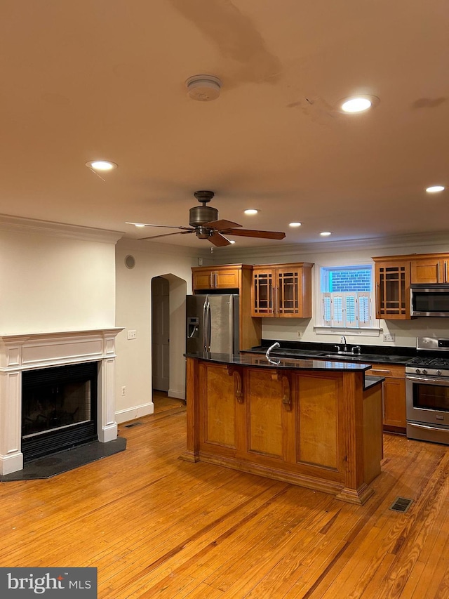 kitchen featuring light wood finished floors, stainless steel appliances, dark countertops, recessed lighting, and crown molding