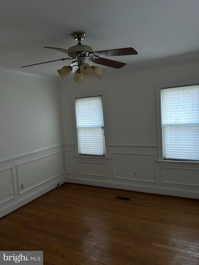 empty room featuring plenty of natural light, visible vents, and crown molding