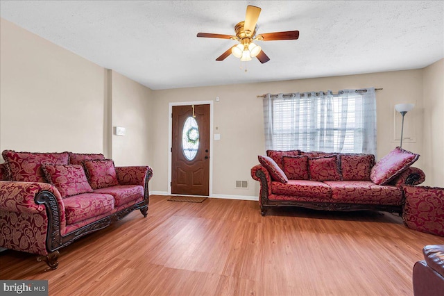 living room featuring ceiling fan, hardwood / wood-style flooring, a textured ceiling, and a wealth of natural light