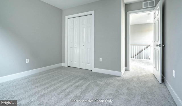 unfurnished bedroom with a closet and light colored carpet