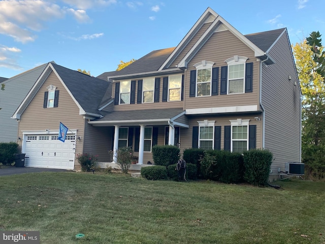 view of front of home with a front yard, central AC unit, and a garage