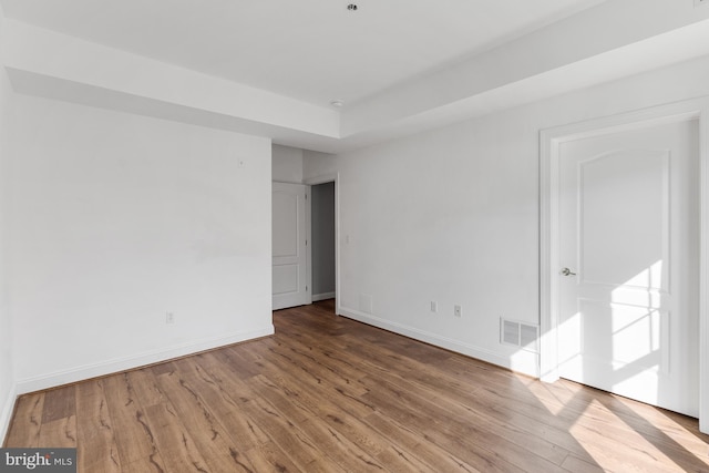unfurnished room with visible vents, baseboards, and wood finished floors
