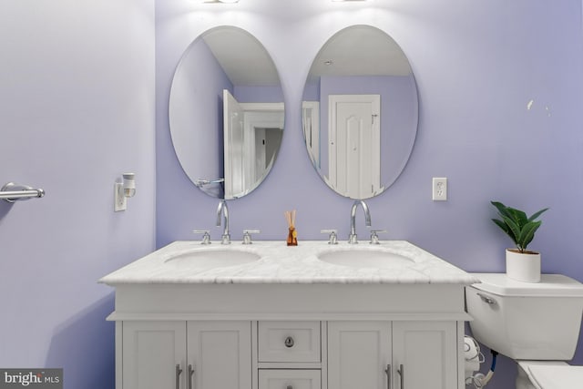 bathroom with double vanity, toilet, and a sink