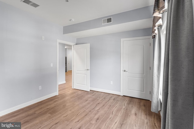 unfurnished bedroom with baseboards, visible vents, and light wood finished floors