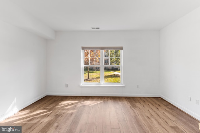 spare room with baseboards, wood finished floors, and visible vents