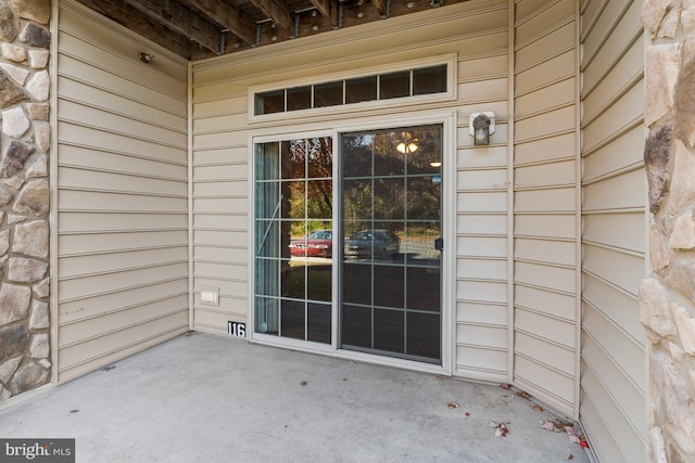 view of exterior entry featuring a patio and stone siding
