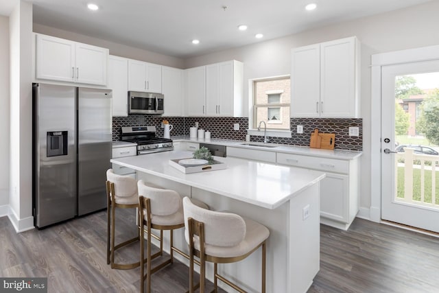 kitchen with white cabinetry, a center island, stainless steel appliances, and sink