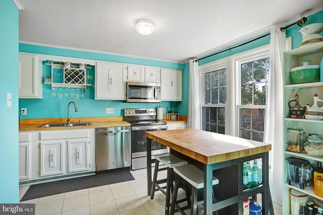 kitchen featuring light tile patterned flooring, sink, white cabinetry, and stainless steel appliances