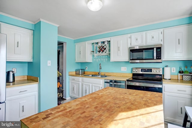 kitchen with stainless steel appliances, white cabinetry, butcher block counters, and sink