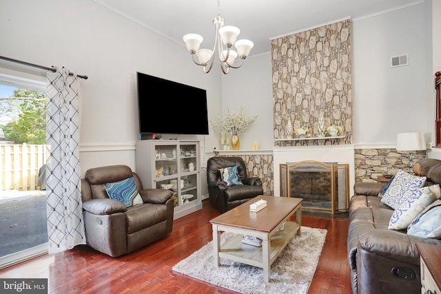 living room with a fireplace, ornamental molding, dark wood-type flooring, and a notable chandelier