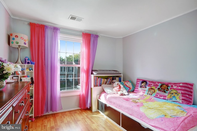 bedroom with light hardwood / wood-style floors and crown molding