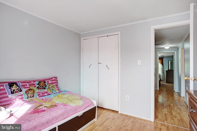 bedroom with light wood-type flooring, a closet, and ornamental molding