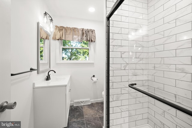 bathroom with a shower with door, vanity, and toilet