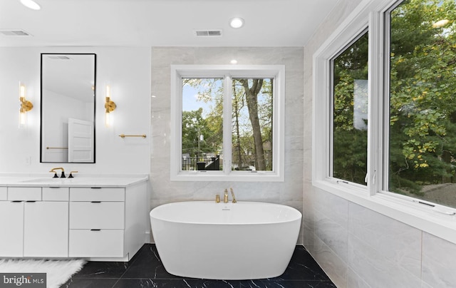 5630 8th St N, Arlington, VA 22205 - bathroom with marble tiled flooring, a freestanding tub, vanity, tile walls, and recessed lighting