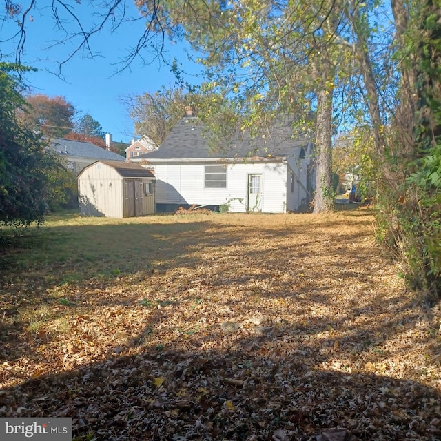 rear view of property featuring a yard and a shed