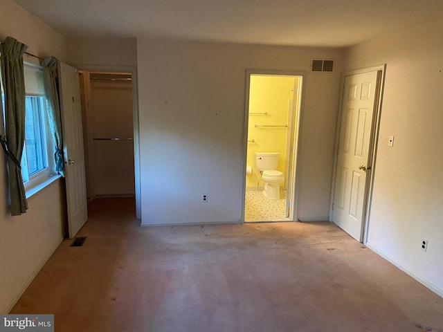 unfurnished bedroom with light carpet, a closet, and ensuite bath