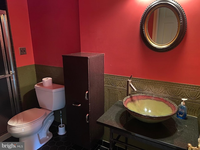 bathroom with toilet, vanity, tile walls, and tile patterned flooring