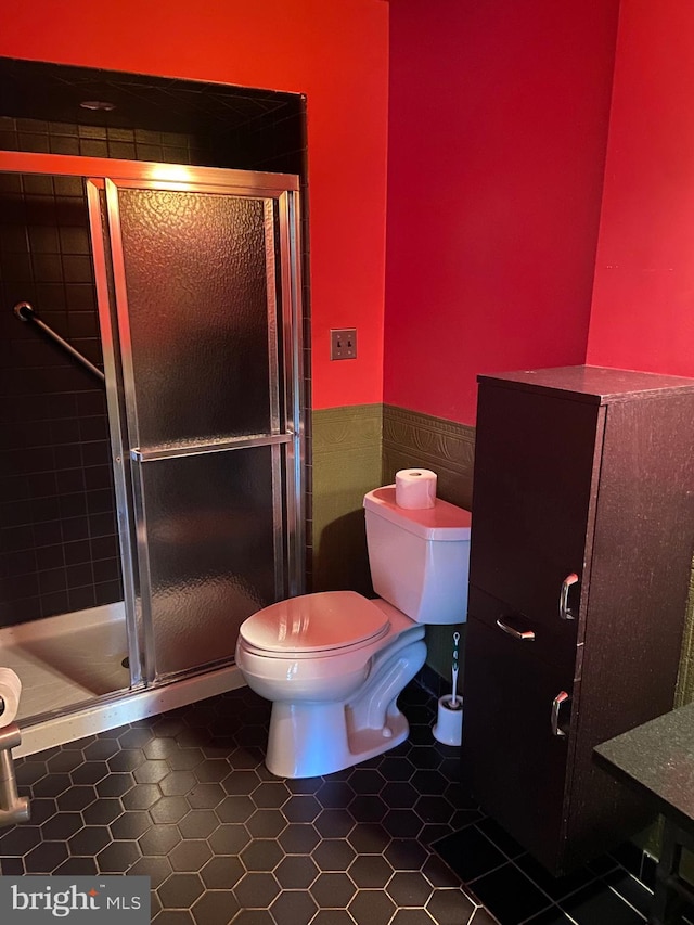 bathroom with toilet, tile patterned floors, and an enclosed shower