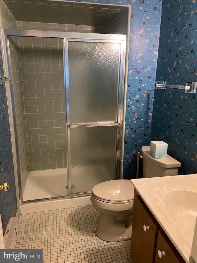 bathroom with vanity, toilet, tile patterned floors, and a shower with door