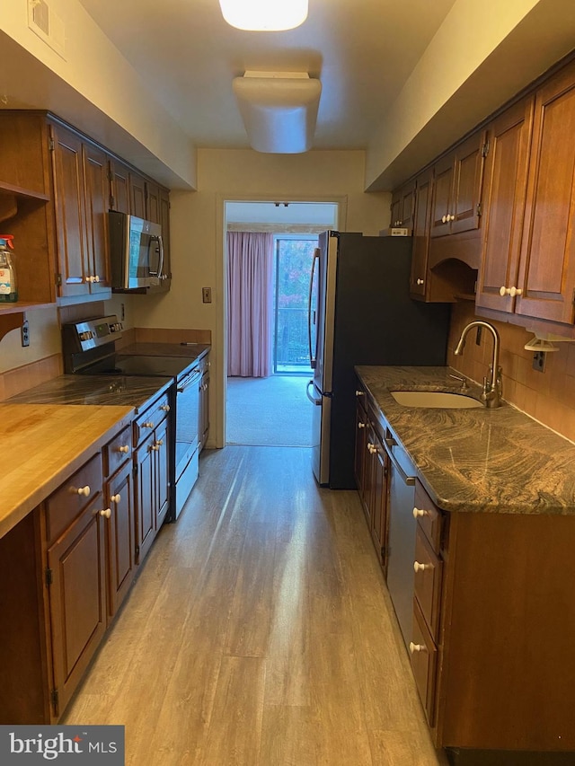 kitchen with wooden counters, decorative backsplash, light hardwood / wood-style flooring, sink, and appliances with stainless steel finishes