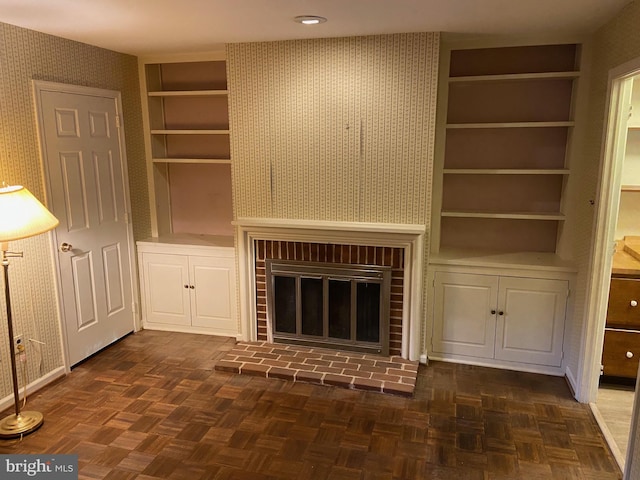 unfurnished living room featuring dark parquet floors, a brick fireplace, and built in features