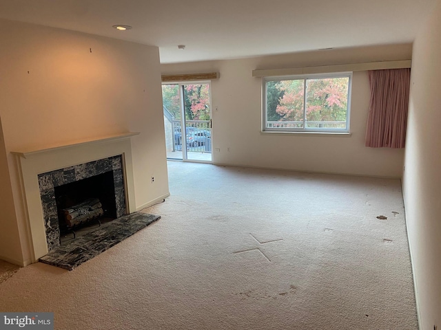 unfurnished living room with a fireplace, light colored carpet, and plenty of natural light