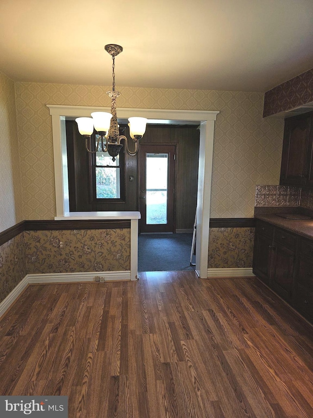 unfurnished dining area featuring a notable chandelier and dark hardwood / wood-style floors