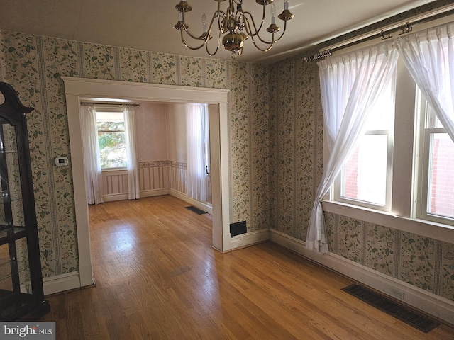 unfurnished dining area with hardwood / wood-style floors and a chandelier