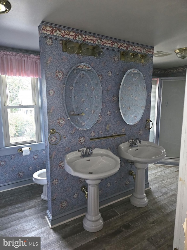 bathroom with dual sinks, wood-type flooring, and toilet