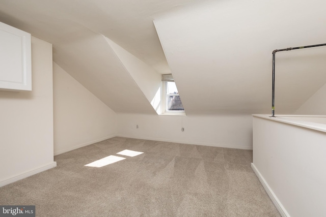 bonus room with lofted ceiling and light colored carpet