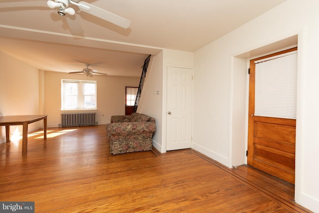 unfurnished room featuring radiator heating unit, wood-type flooring, and ceiling fan