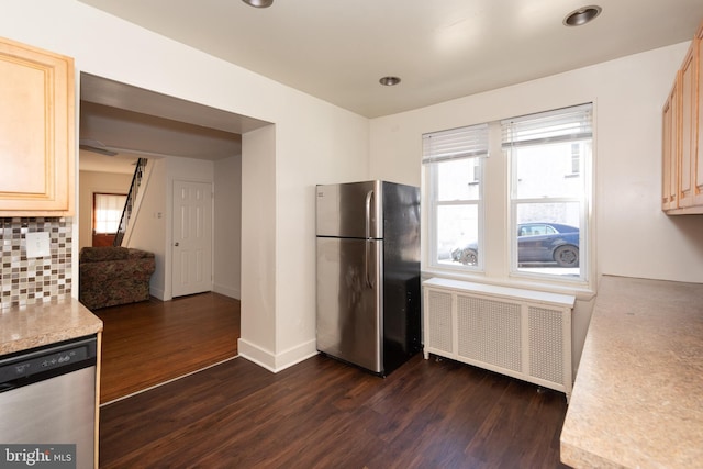 kitchen featuring radiator, stainless steel appliances, light brown cabinetry, and dark wood-type flooring