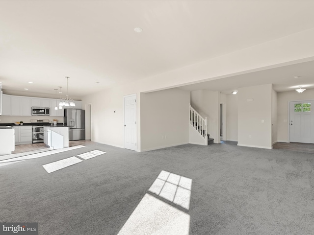 unfurnished living room with carpet and a notable chandelier