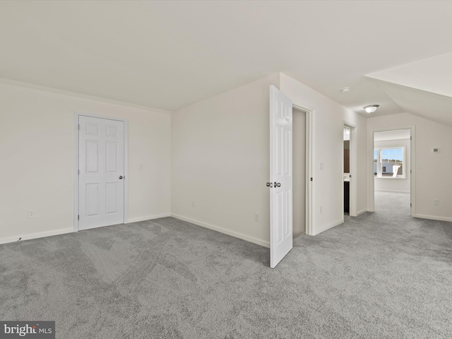 bonus room with light colored carpet and vaulted ceiling