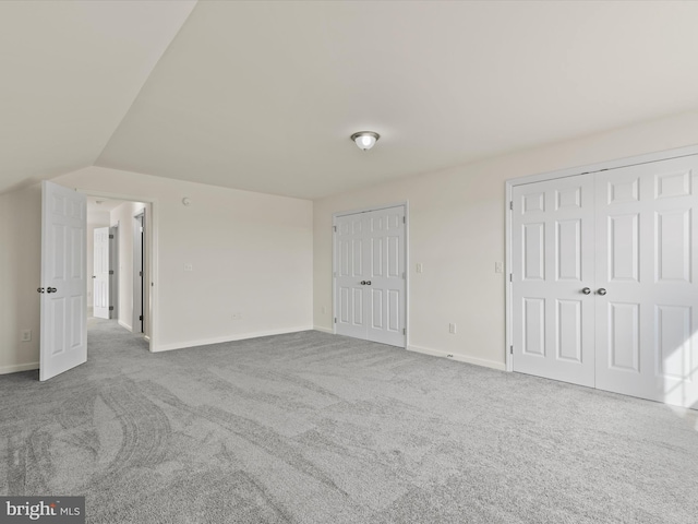 unfurnished bedroom with lofted ceiling, multiple closets, and carpet flooring