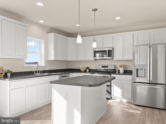 kitchen featuring a kitchen island, white cabinetry, stainless steel appliances, sink, and decorative light fixtures