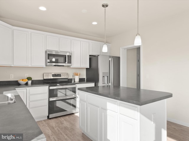 kitchen with a center island, hanging light fixtures, white cabinetry, stainless steel appliances, and light hardwood / wood-style flooring