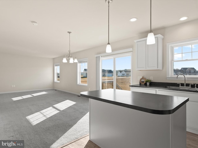 kitchen featuring sink, plenty of natural light, a kitchen island, and white cabinets