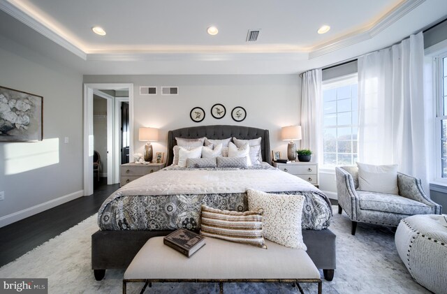 bedroom featuring a raised ceiling, wood-type flooring, and ornamental molding