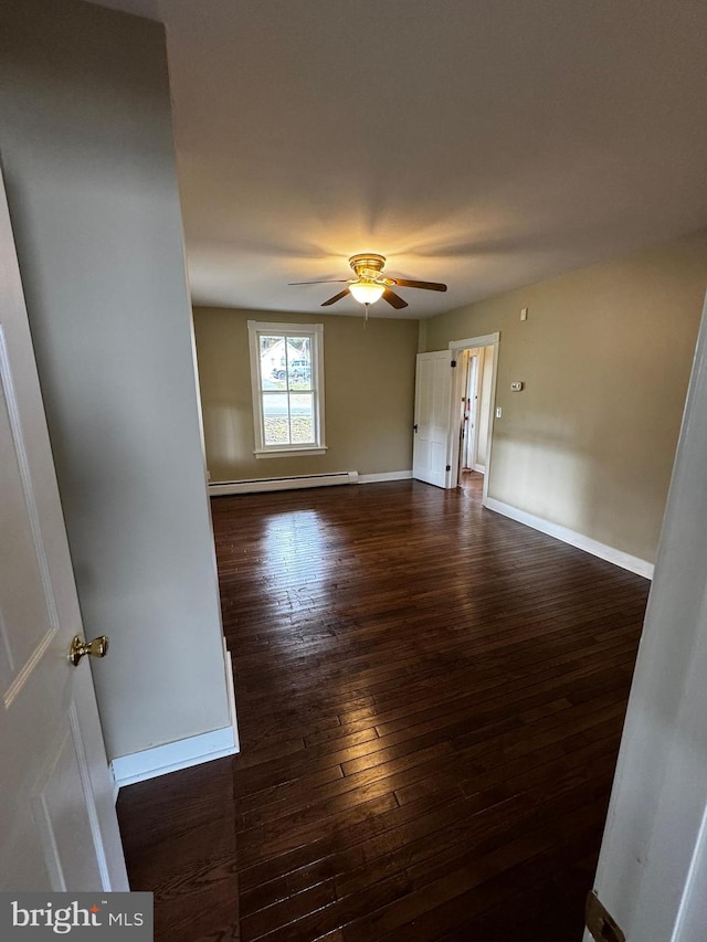 empty room featuring dark wood-type flooring, a baseboard radiator, and ceiling fan