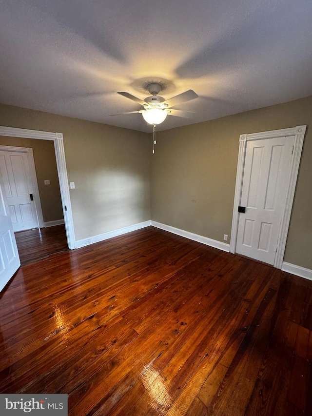 unfurnished room with a textured ceiling, dark wood-type flooring, and ceiling fan