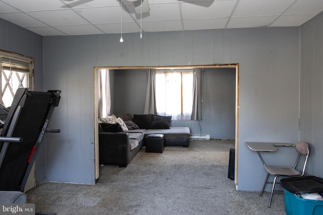 carpeted living room featuring a baseboard heating unit and a paneled ceiling