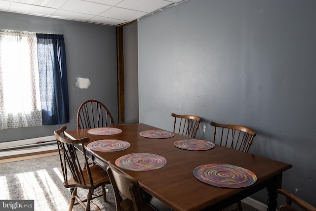 carpeted dining area featuring a drop ceiling