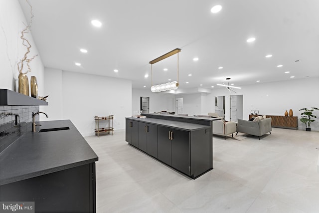 kitchen featuring a spacious island, sink, pendant lighting, and backsplash