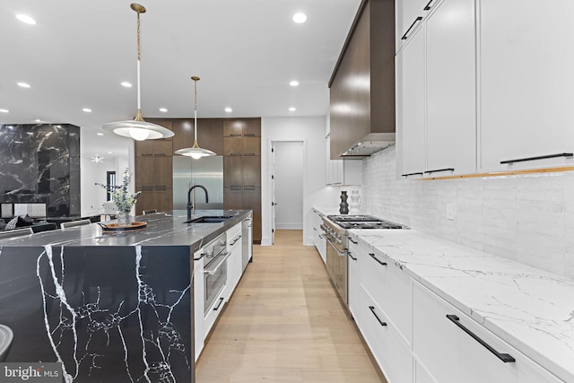 kitchen with sink, white cabinets, light stone counters, and pendant lighting