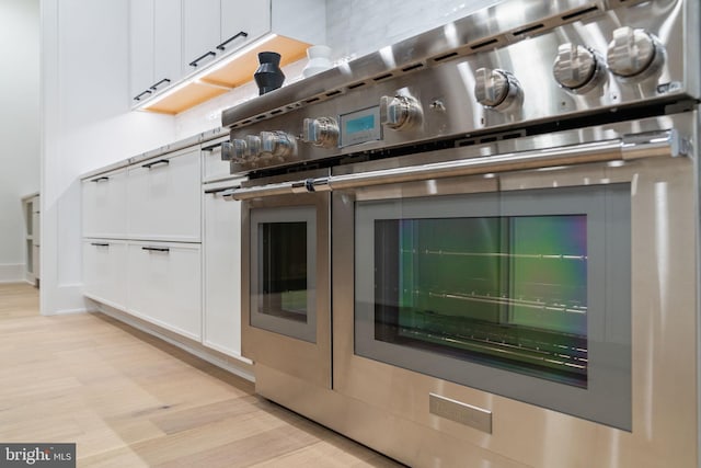 interior space featuring white cabinets, light hardwood / wood-style floors, and stainless steel stove