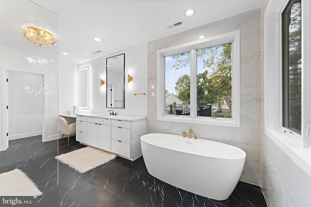 bathroom featuring vanity, a tub, and tile walls