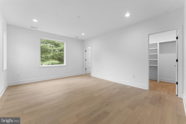 unfurnished bedroom featuring a spacious closet and light hardwood / wood-style floors